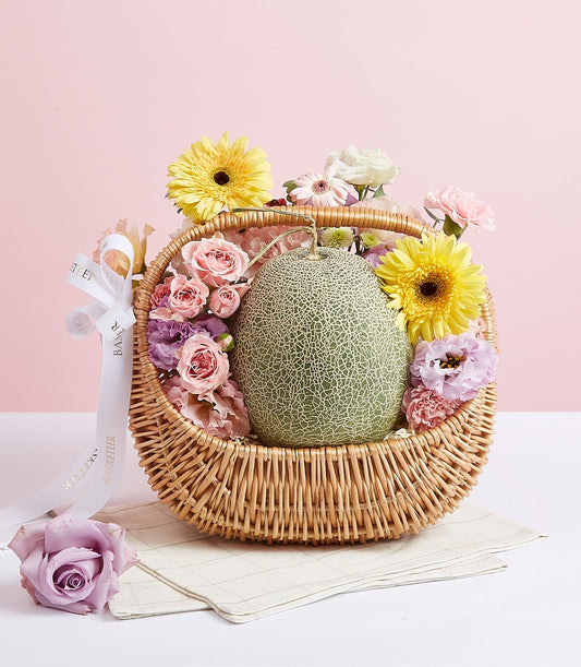 Premium fresh melon with pink roses, yellow daisies, and purple carnations in woven gift basket