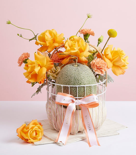 Premium cantaloupe melon with yellow roses and peach carnations in luxury gift basket