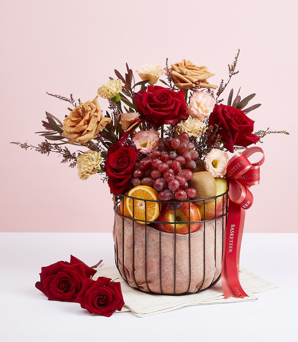 Premium mixed fruit and red roses in black wire basket with cream carnations and fresh grapes
