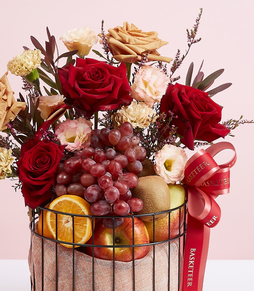 Premium fruit and red rose gift basket with grapes, apples, and fresh flowers in black wire basket