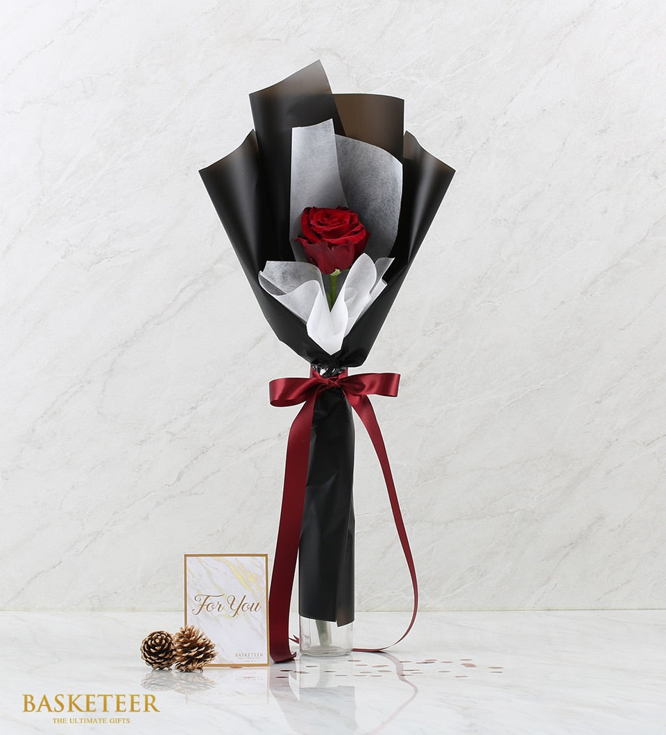 Single red rose in glass vase with black tissue wrap and burgundy satin ribbon, paired with For You card and pinecones