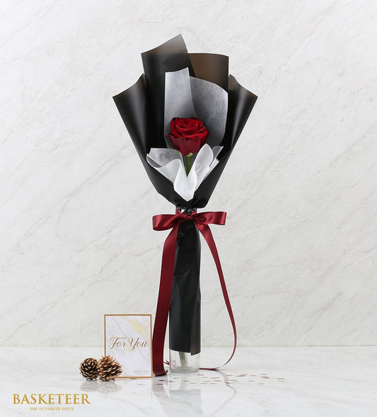 Single red Ecuadorian rose with black and white tissue wrap, satin ribbon bow in clear glass vase