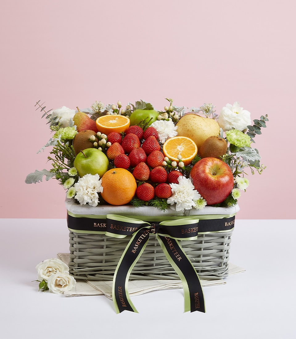 Mixed fruit and white flower gift basket with red strawberries, apples, and citrus for birthdays and celebrations
