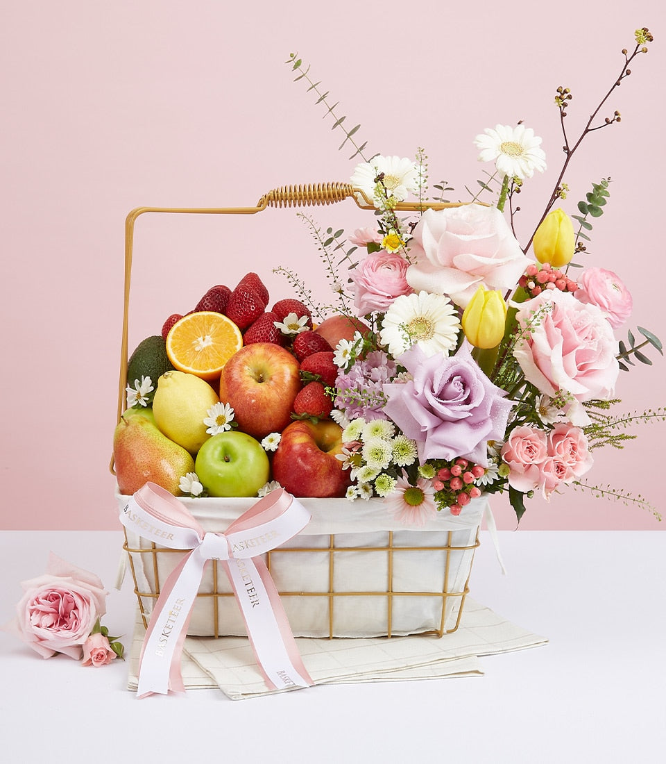 Gold wire basket with fresh fruit and pink roses, strawberries, and tulips for birthday gifting