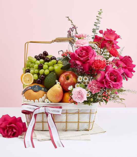 Luxury mixed fruit and rose gift basket with fresh grapes, citrus, and fuchsia flowers on gold wire frame
