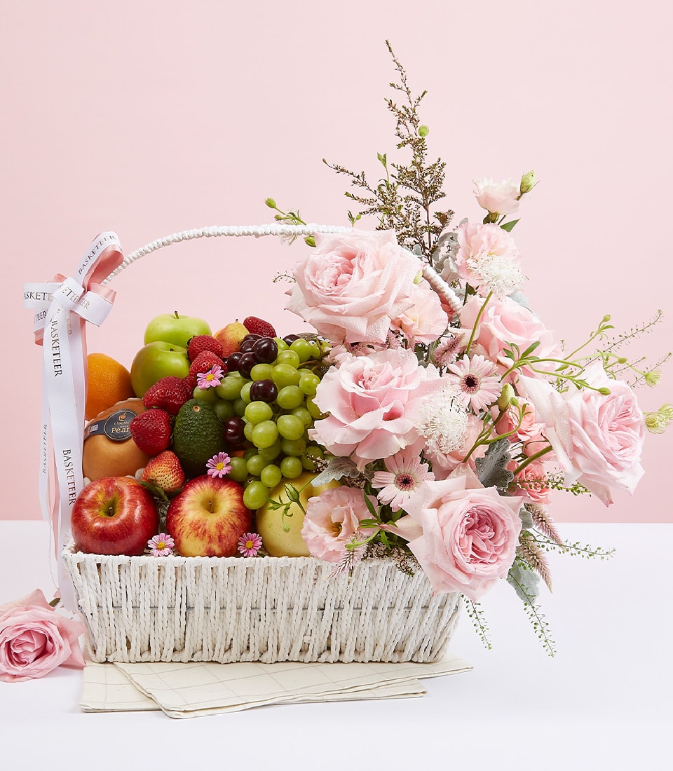 Pink rose and fresh fruit gift basket with gerbera daisies in white woven design