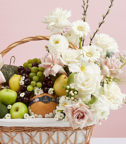Premium fruit and flower gift basket with fresh grapes, apples, pears, and white roses in woven wicker