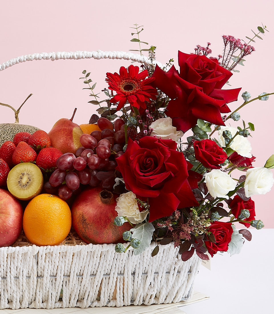 Luxury red roses and fresh fruit gift basket with strawberries, grapes, and seasonal produce