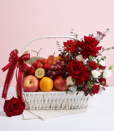 Premium red roses and fresh fruit gift basket with cantaloupe, grapes, berries in white woven basket