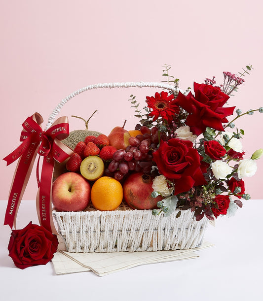 Premium red roses and fresh fruit gift basket with cantaloupe, grapes, berries in white woven basket