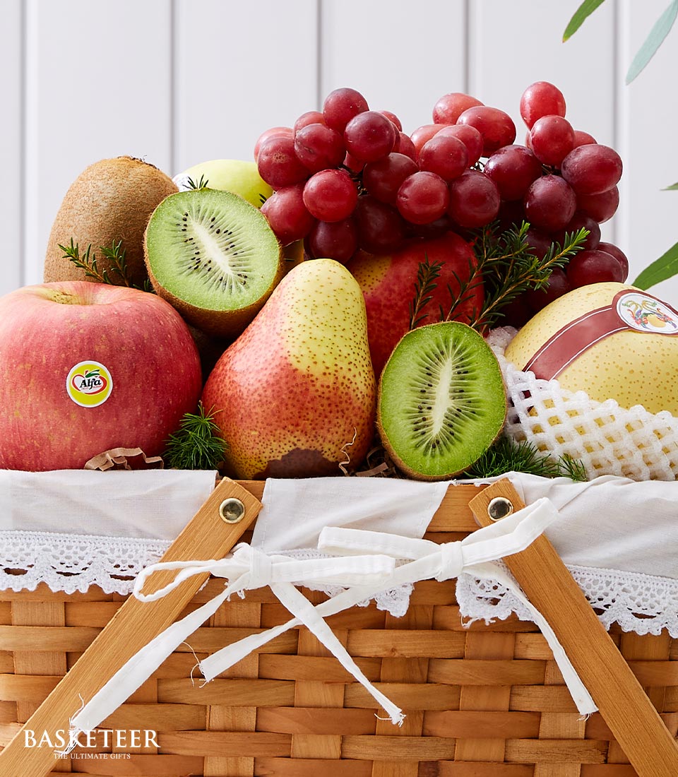 Woven fruit gift basket with fresh apples, kiwis, grapes, pears and white ribbon bow