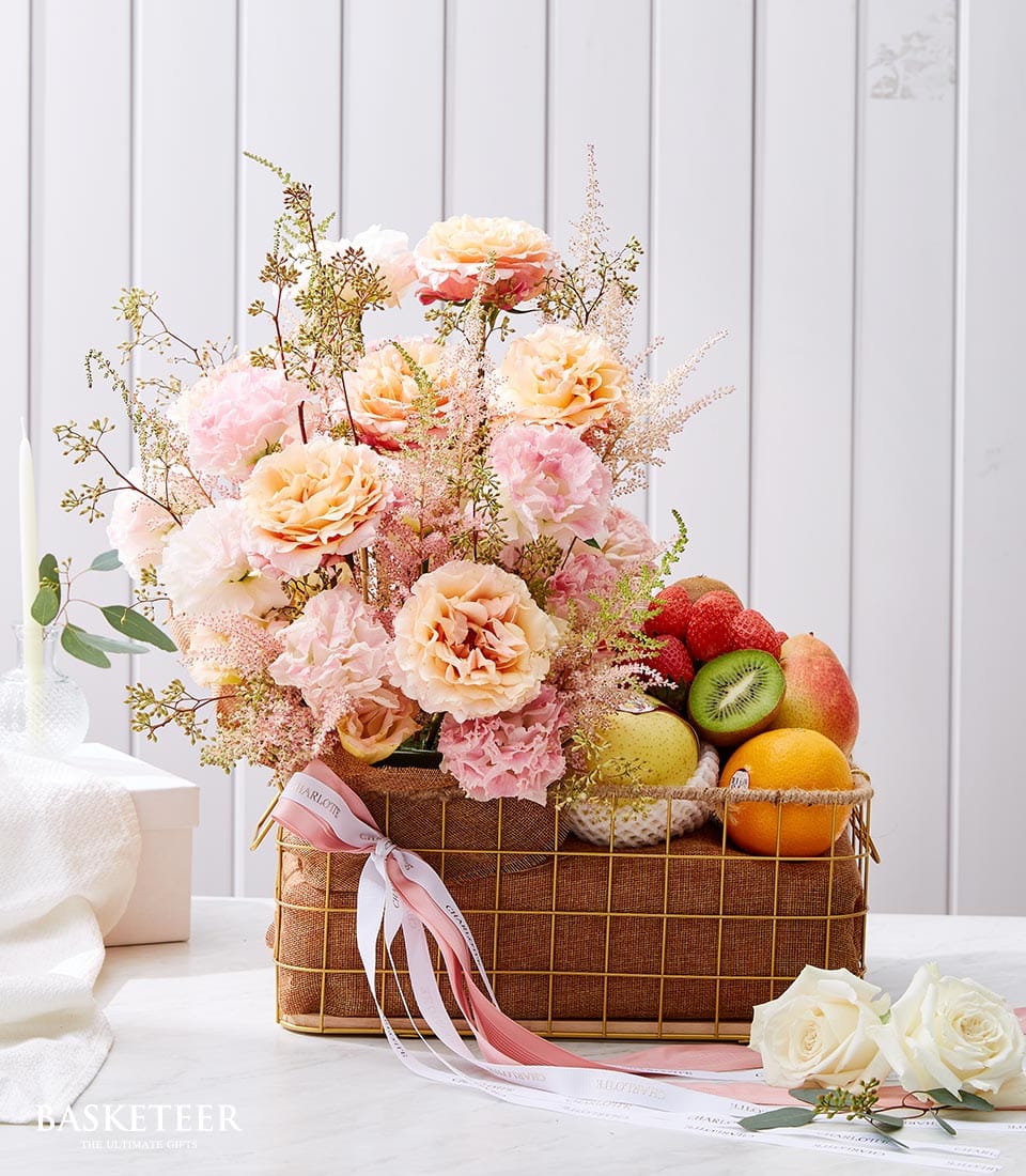 Luxury gift basket with pink roses, carnations, fresh strawberries, kiwi, pear, and apple in woven brown basket