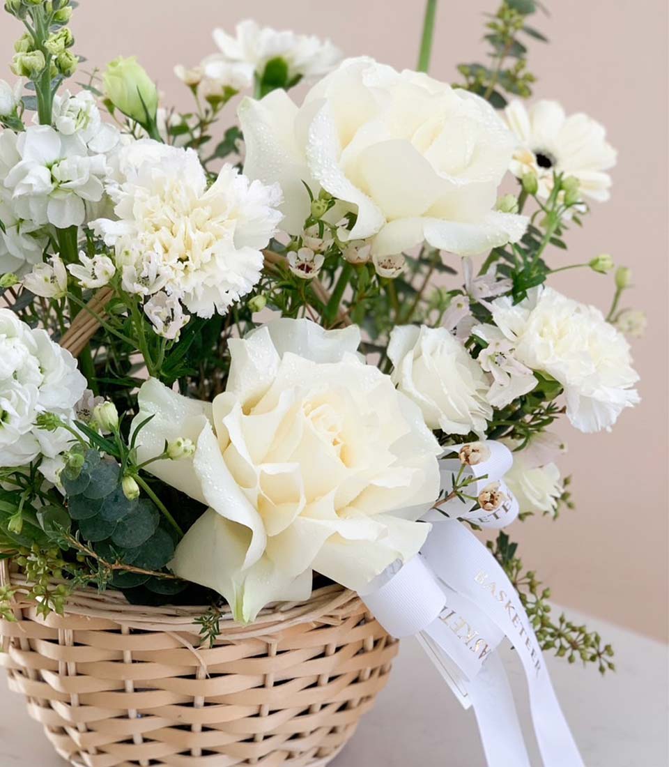 White rose and carnation arrangement in woven basket with ribbon, perfect for graduation congratulations