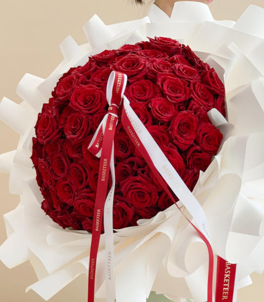 Luxurious red roses bouquet wrapped in cream paper with cascading ribbon, anniversary gift for her
