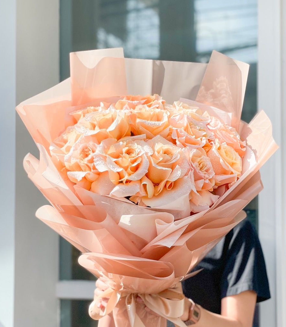 Fresh peach rose bouquet with dewy petals, wrapped in layered blush paper with satin ribbon bow