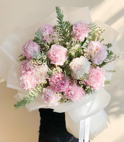Blush pink and white peony bouquet with green foliage, wrapped in white paper with satin ribbon