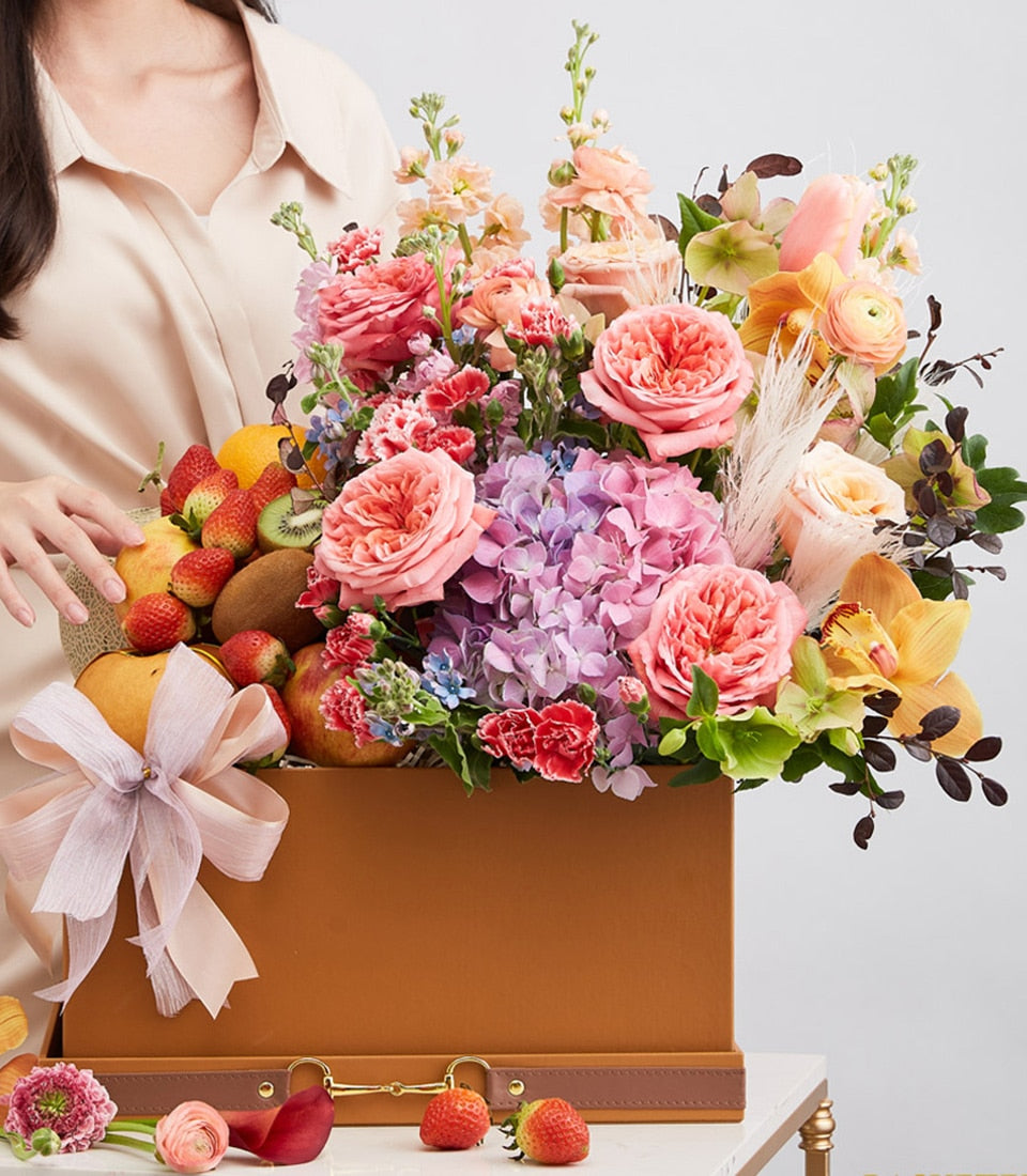 Luxury brown leather gift box with fresh strawberries, kiwis, pears, apples and lush pink roses, hydrangeas, orchids in