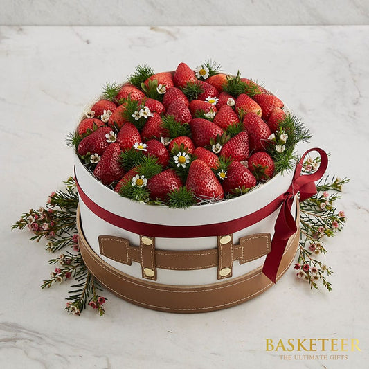 Premium fresh strawberry gift box with white ribbon and leather-look base, topped with white daisies and green foliage