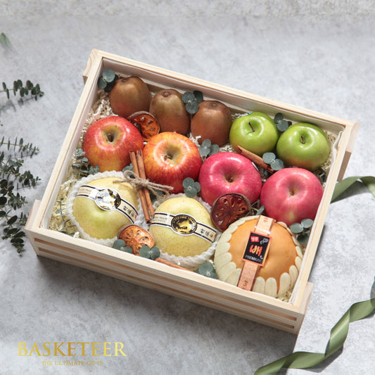 Wooden gift box filled with fresh kiwis, apples, pears, and cinnamon nestled in white shredded paper by Basketeer
