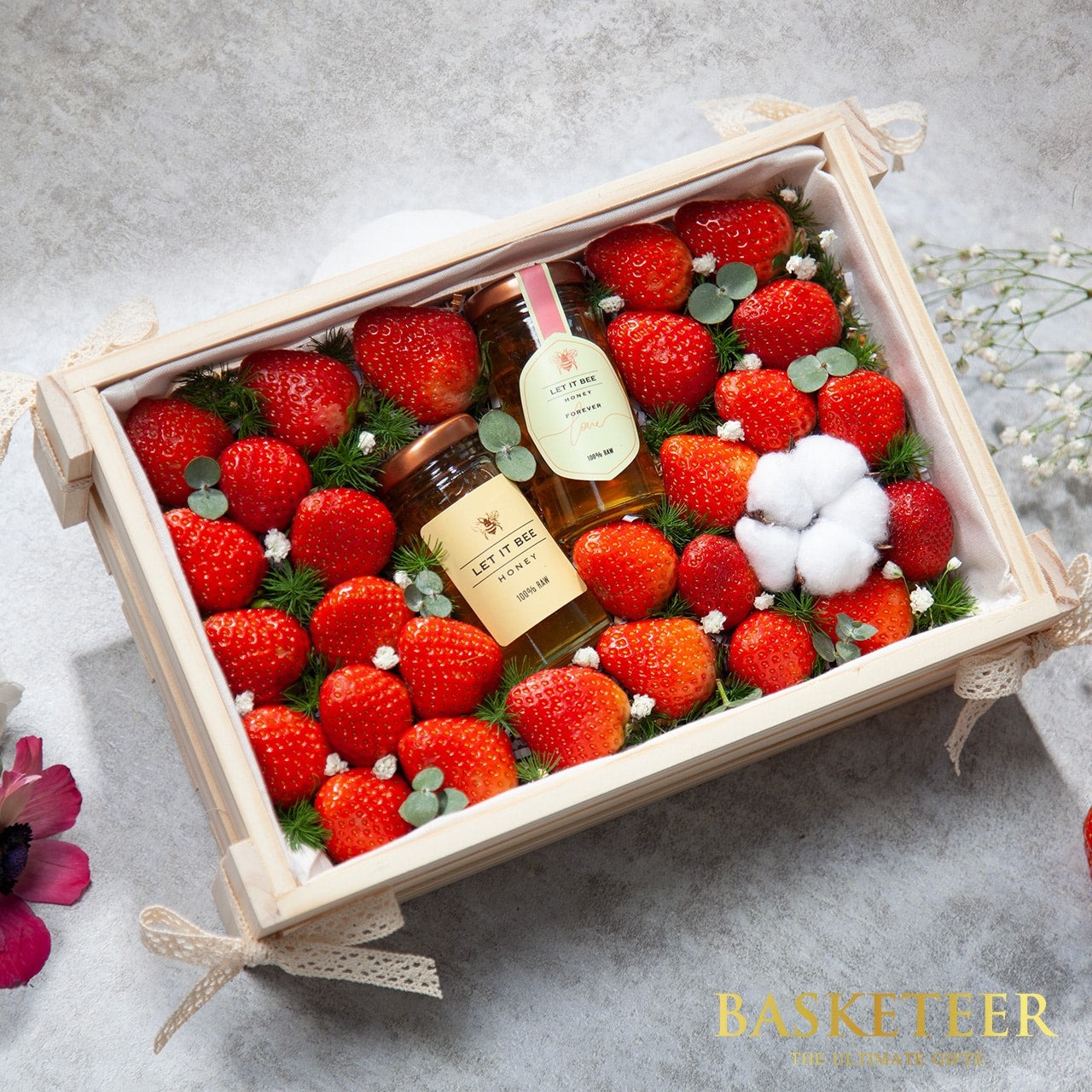 Fresh strawberries and raw honey in wooden gift box with white lace ribbons