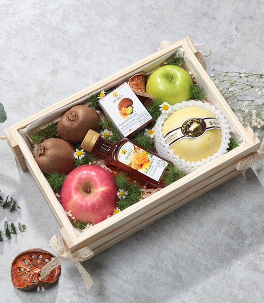 Deluxe wooden crate with fresh kiwis, apples, pear, honey, and gourmet wellness products on shredded paper