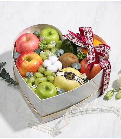 Heart-shaped premium fruit gift box with red apples, grapes, kiwis, and pomegranate, white marble design with gold trim and