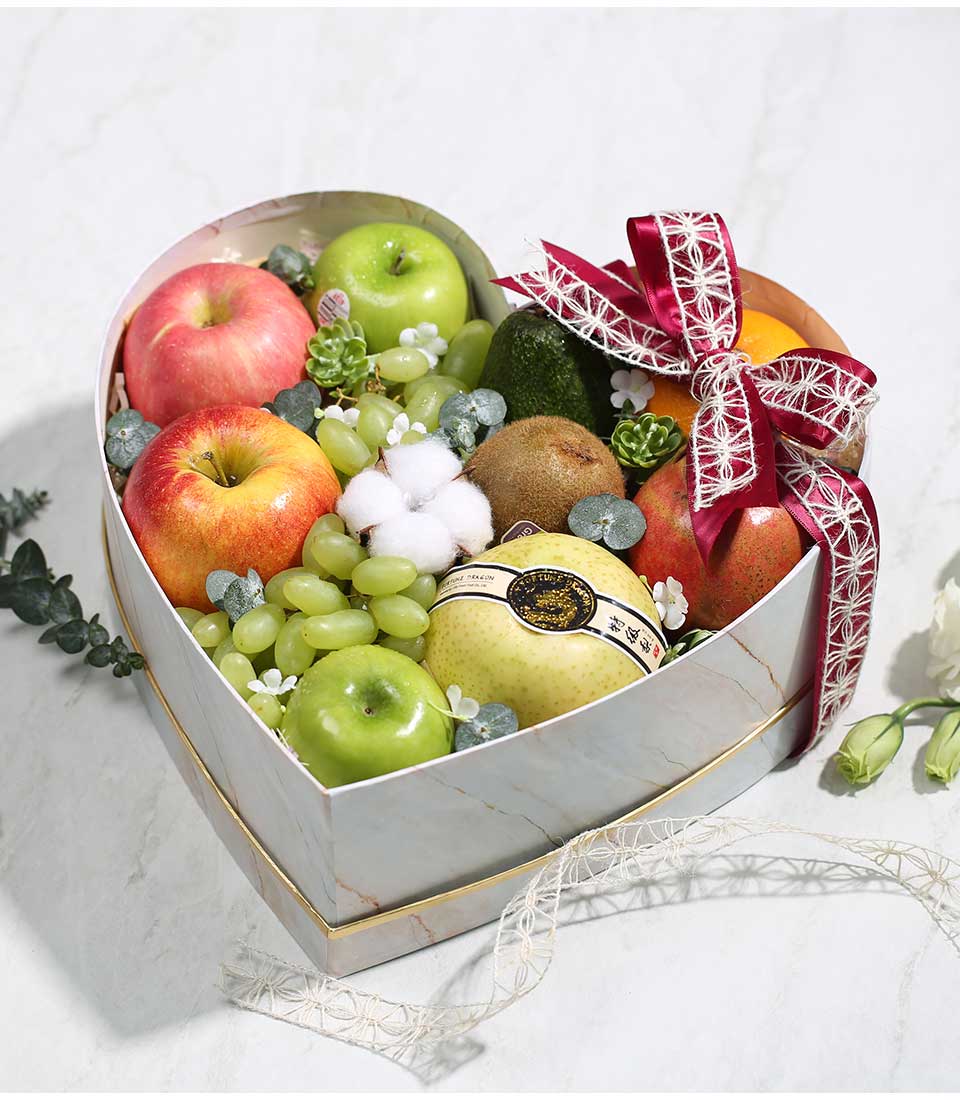 Heart-shaped premium fruit gift box with red apples, grapes, kiwis, and pomegranate, white marble design with gold trim and