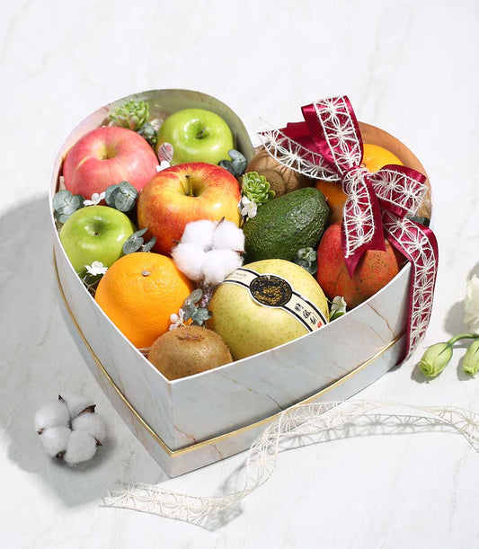 Heart-shaped marble gift box filled with fresh fruits, succulents, and white blossoms for birthday gifting