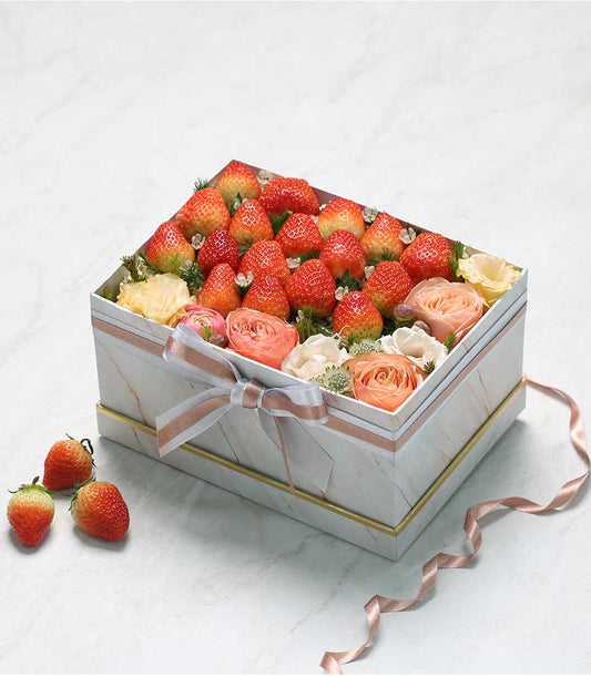 Fresh strawberries and peach roses in elegant white marble gift box with rose gold trim