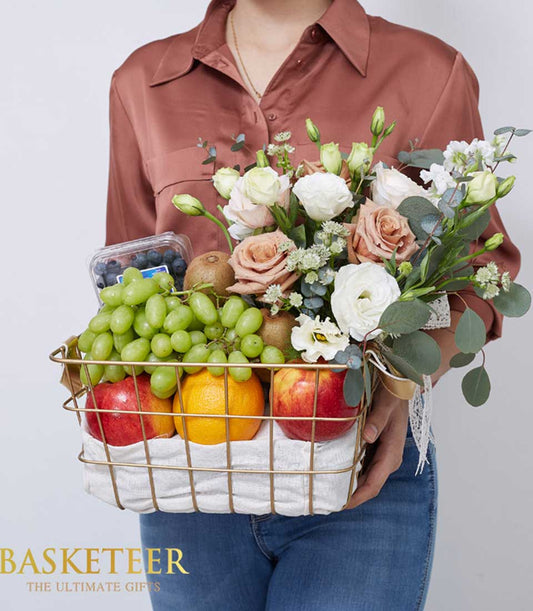Luxe gold wire basket overflowing with fresh grapes, berries, kiwi, apples, oranges and white peach roses with eucalyptus