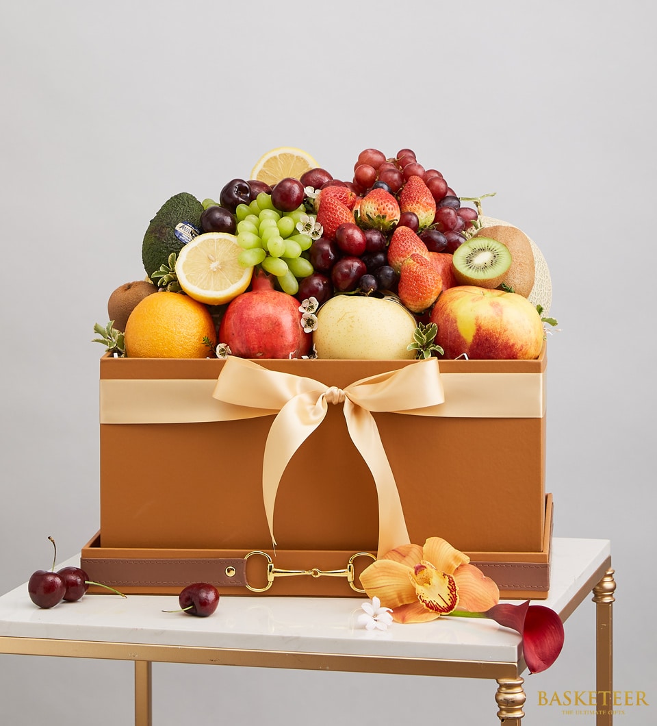Luxury leather fruit gift box with fresh assorted produce, gold ribbon, and floral accents on marble table