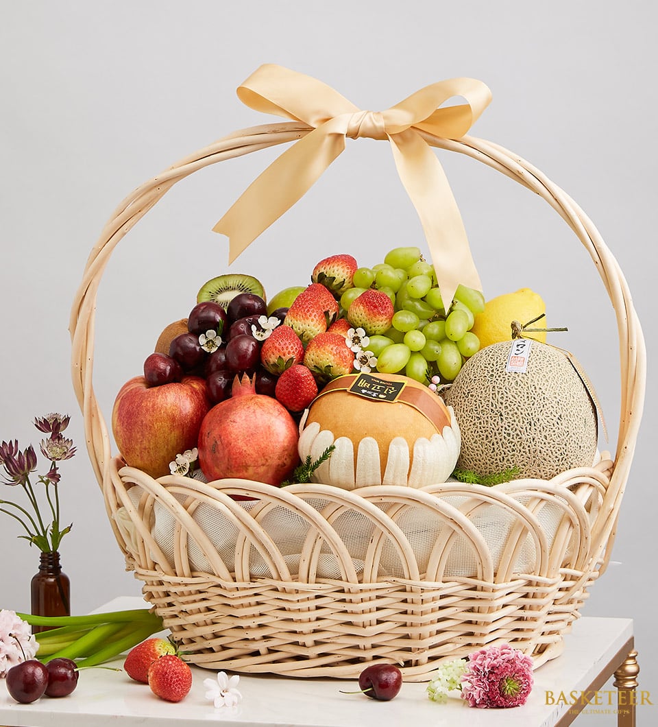Basketeer premium hamper delivery Thailand: Wicker basket brimming with fresh fruit gift. Includes grapes, melon, strawberries and a gold ribbon.