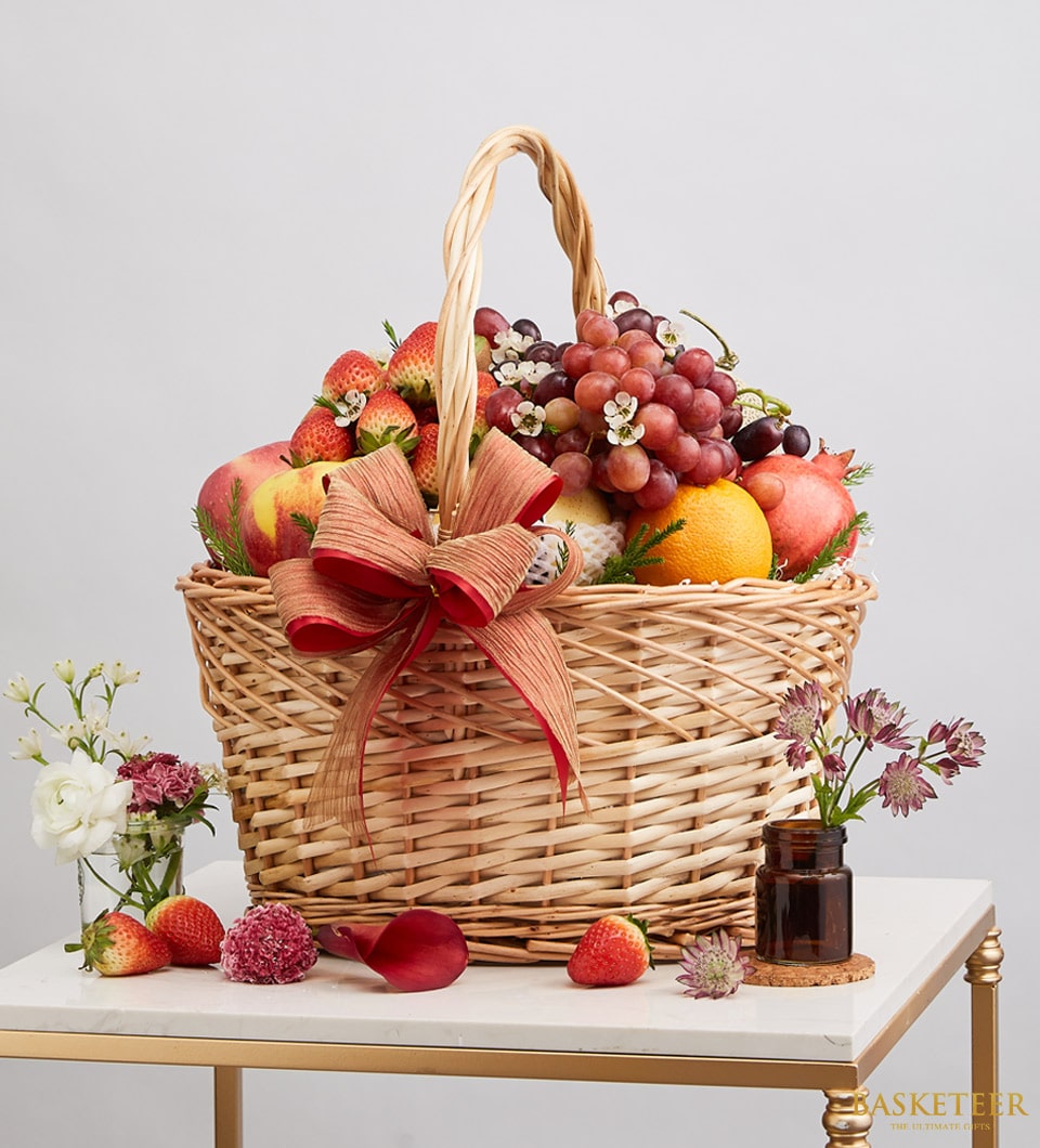 Premium wicker fruit basket with fresh grapes, strawberries, apples and pomegranate, finished with burgundy ribbon bow