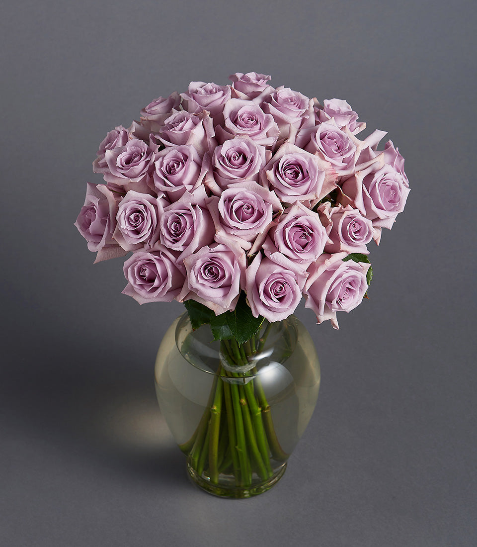 Lavender roses in clear glass sphere vase with green stems, minimalist elegant arrangement