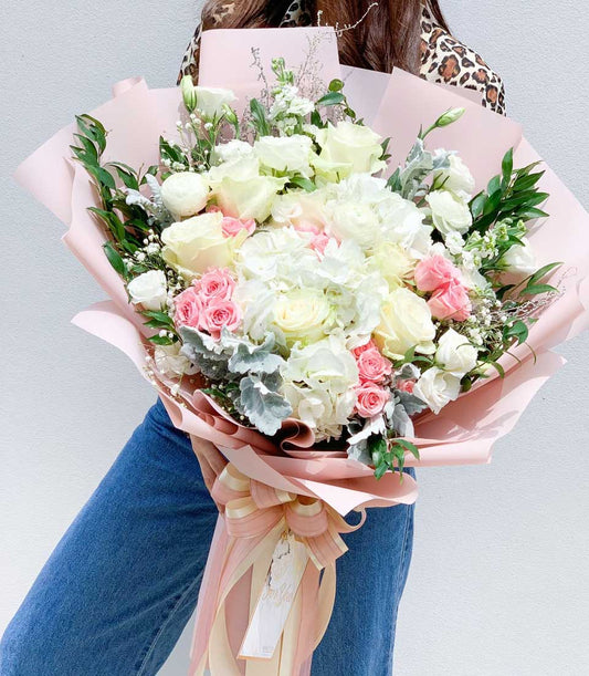 Rosy Elegance bouquet of white and blush roses with hydrangeas, wrapped in soft pink paper and ribbon bow