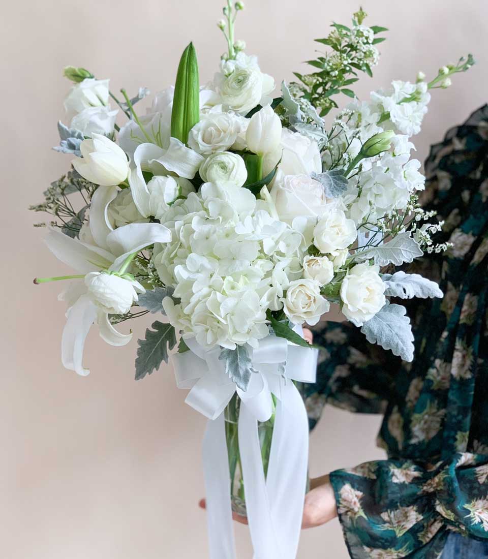 Luxurious white hydrangea, rose, and lily bouquet in glass vase with satin ribbon, perfect birthday congratulations flowers