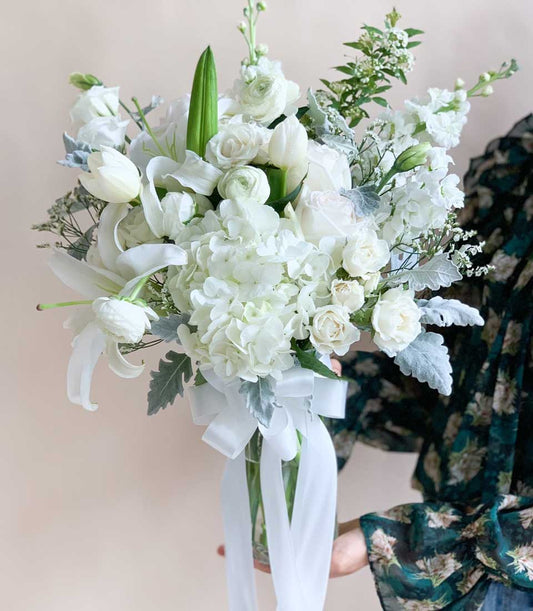 Luxurious white hydrangea, rose, and lily bouquet in glass vase with satin ribbon, perfect birthday congratulations flowers