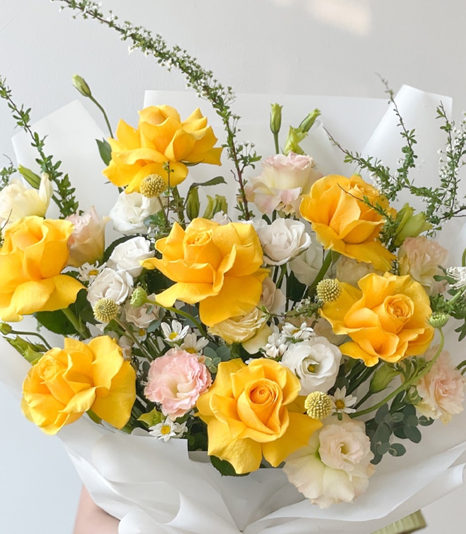 Sunny yellow rose bouquet with white lisianthus and baby's breath, wrapped in white paper for graduation