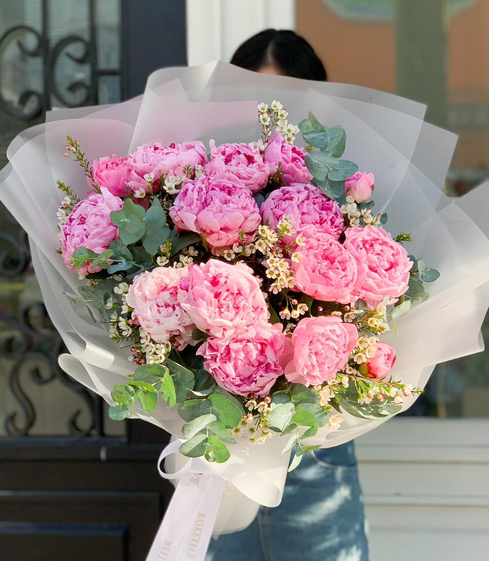 Luxe pink peony bouquet with eucalyptus and white filler flowers, wrapped in layered tissue and white ribbon
