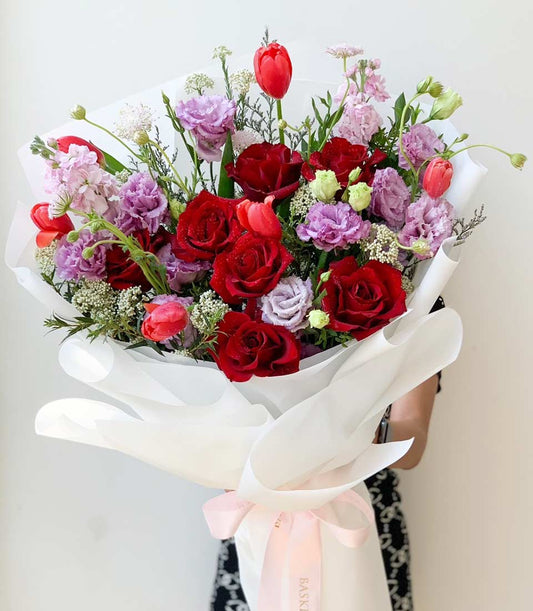Luxe red roses and lavender eustoma bouquet with white wrapper and pink ribbon, fresh flower gift