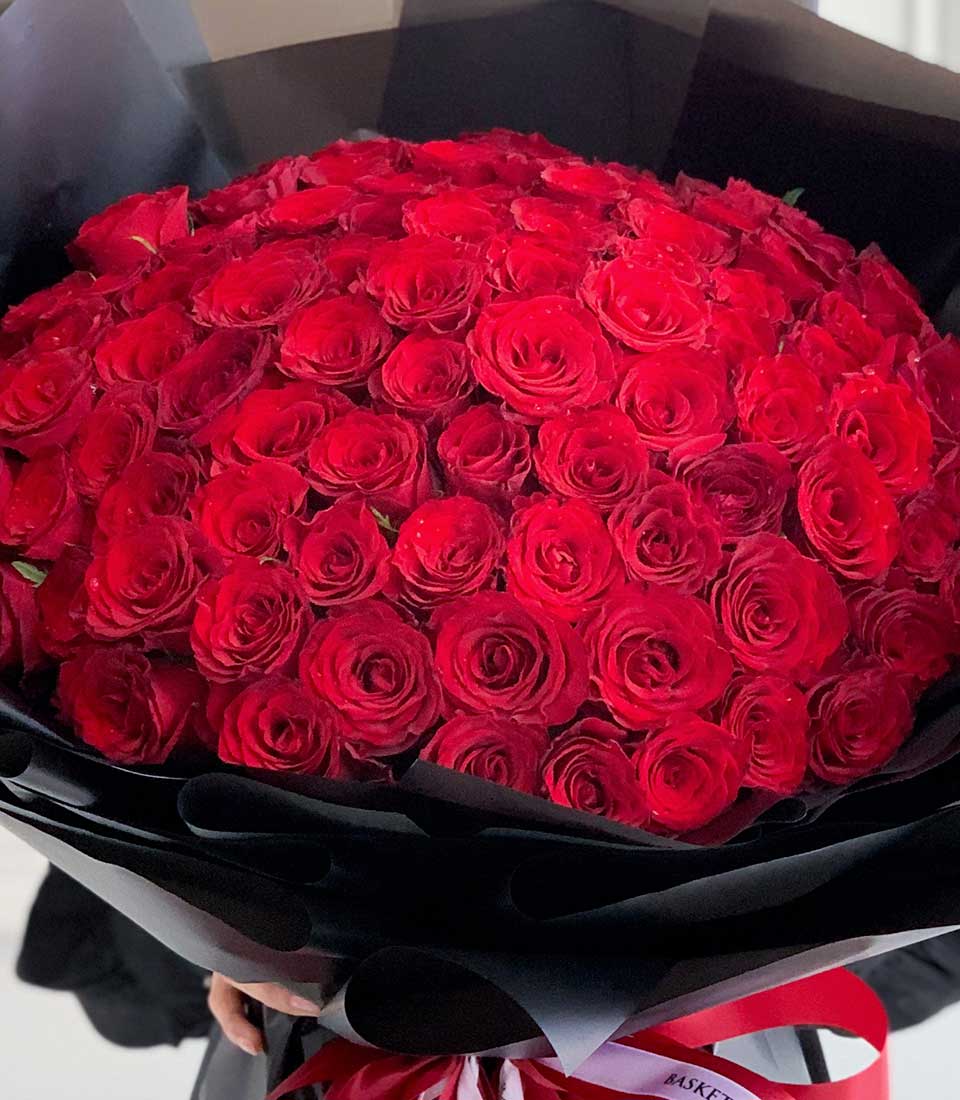 Premium red rose bouquet with black paper wrapping and red ribbon bow, luxury Valentine's Day flowers