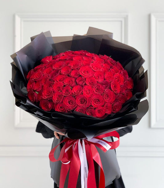 Luxurious red rose dome bouquet wrapped in dramatic black paper with red ribbon for Valentine's Day