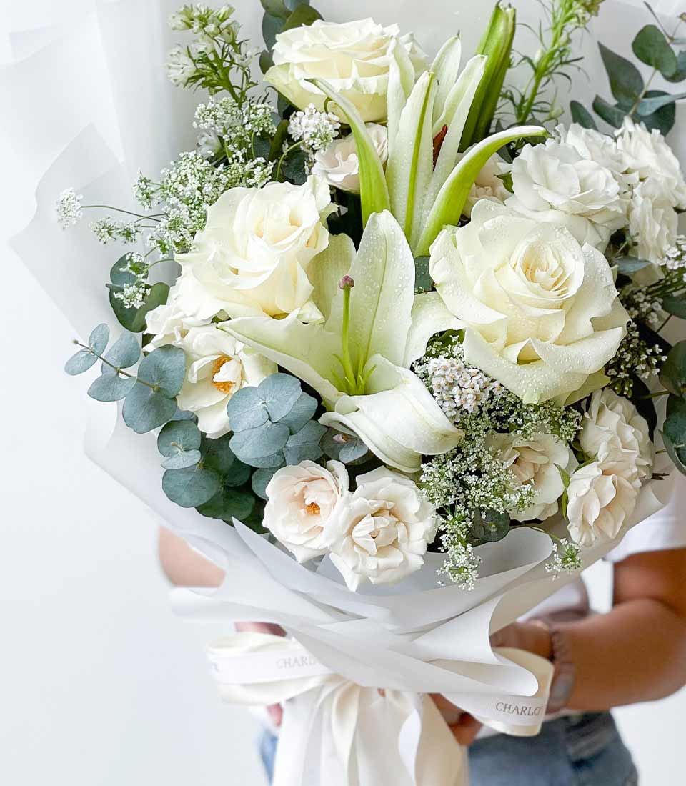 Fresh white roses and lilies graduation bouquet with eucalyptus, wrapped in white paper