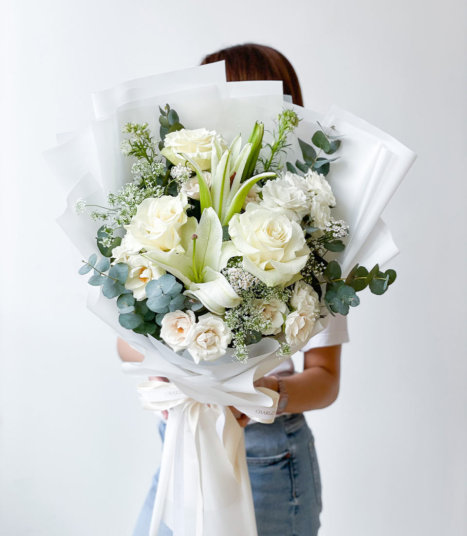 Elegant white rose and lily graduation bouquet with eucalyptus, wrapped in white paper and ribbon