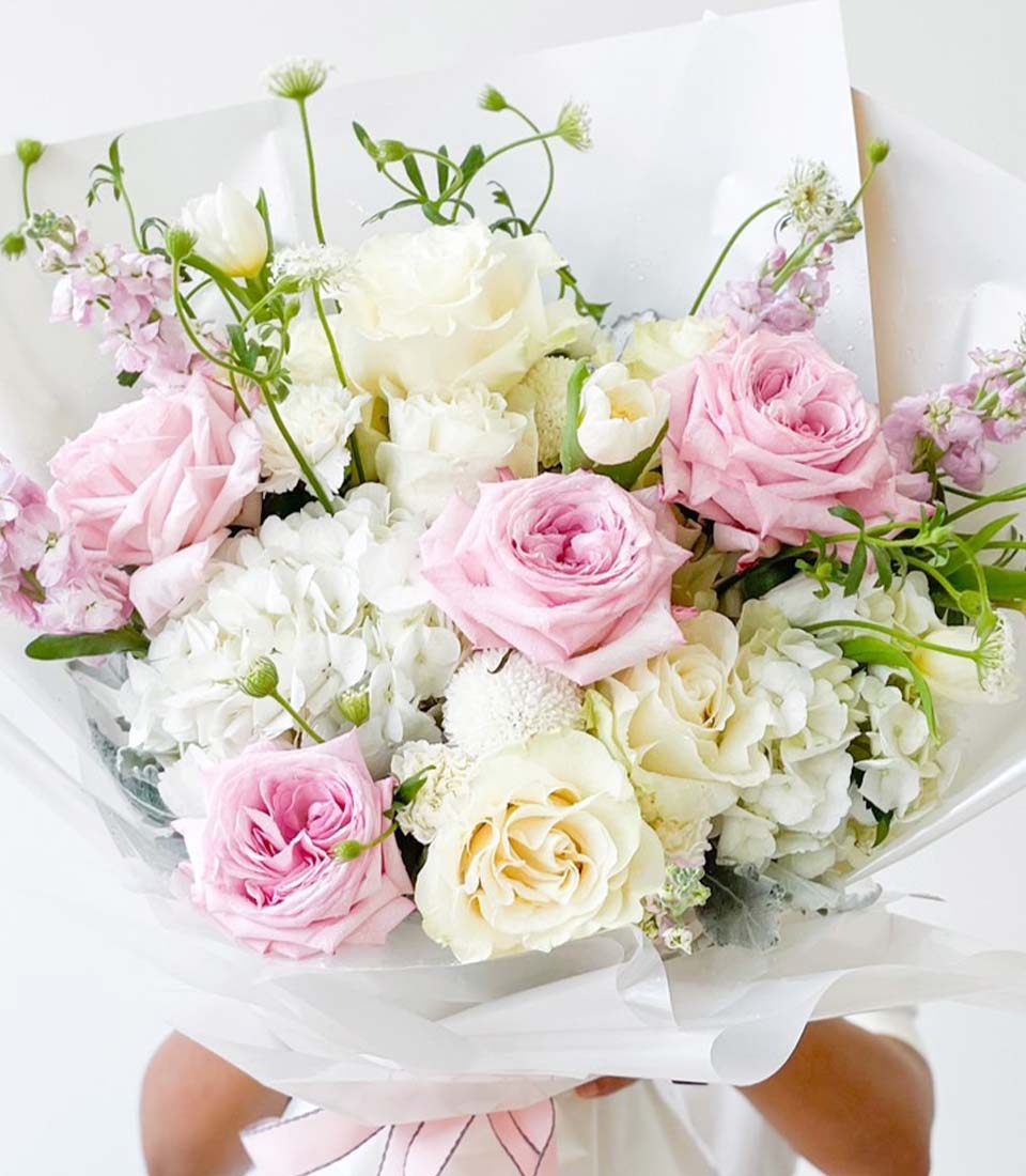 Pink and white rose bouquet with hydrangeas, wrapped in cellophane with pink ribbon for birthdays