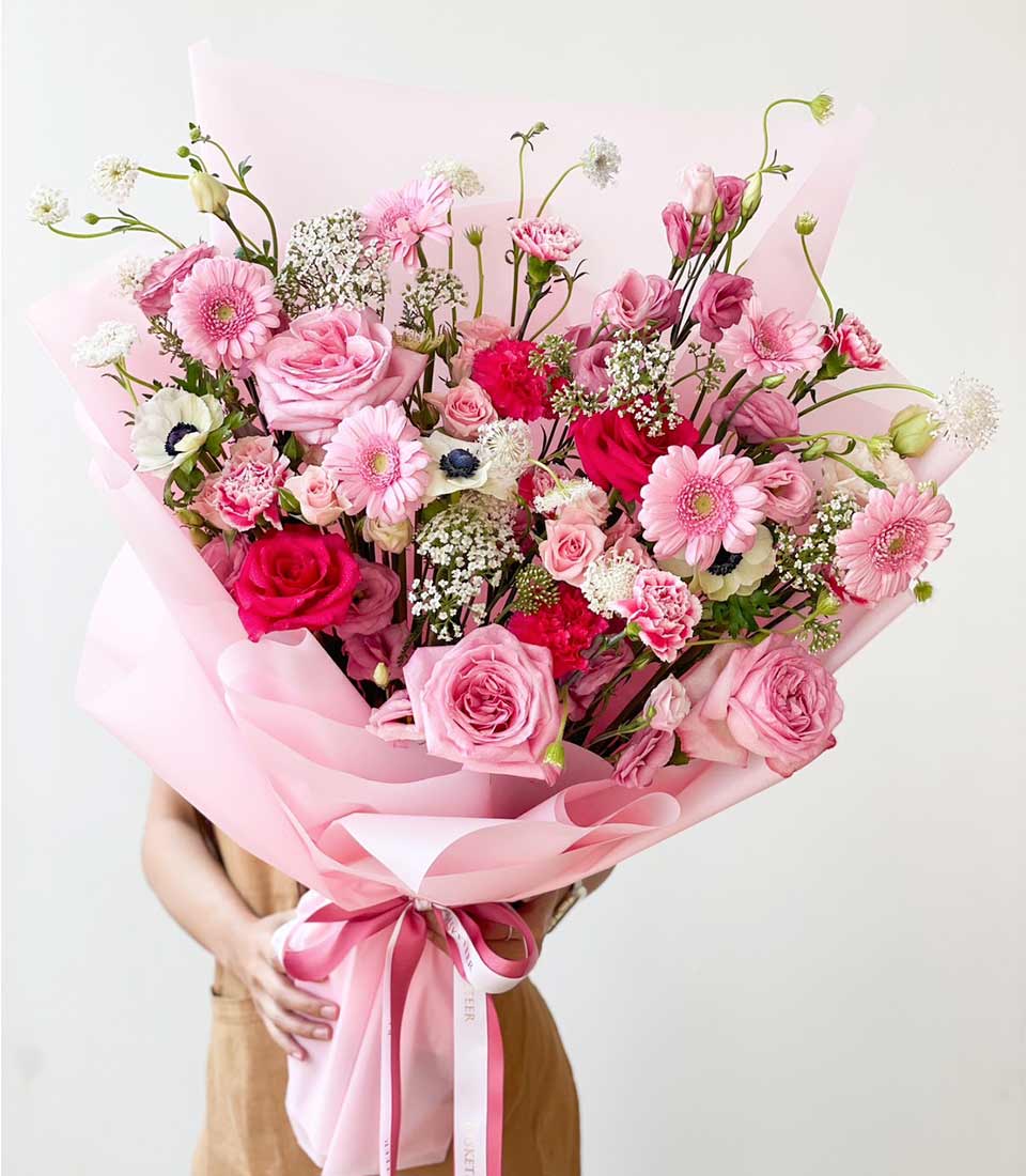 Vibrant pink rose and gerbera bouquet wrapped in blush paper with double ribbon bow