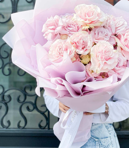 Enchanted Elegance light pink garden roses bouquet with cream accents, wrapped in soft pink tissue and white ribbon, perfect
