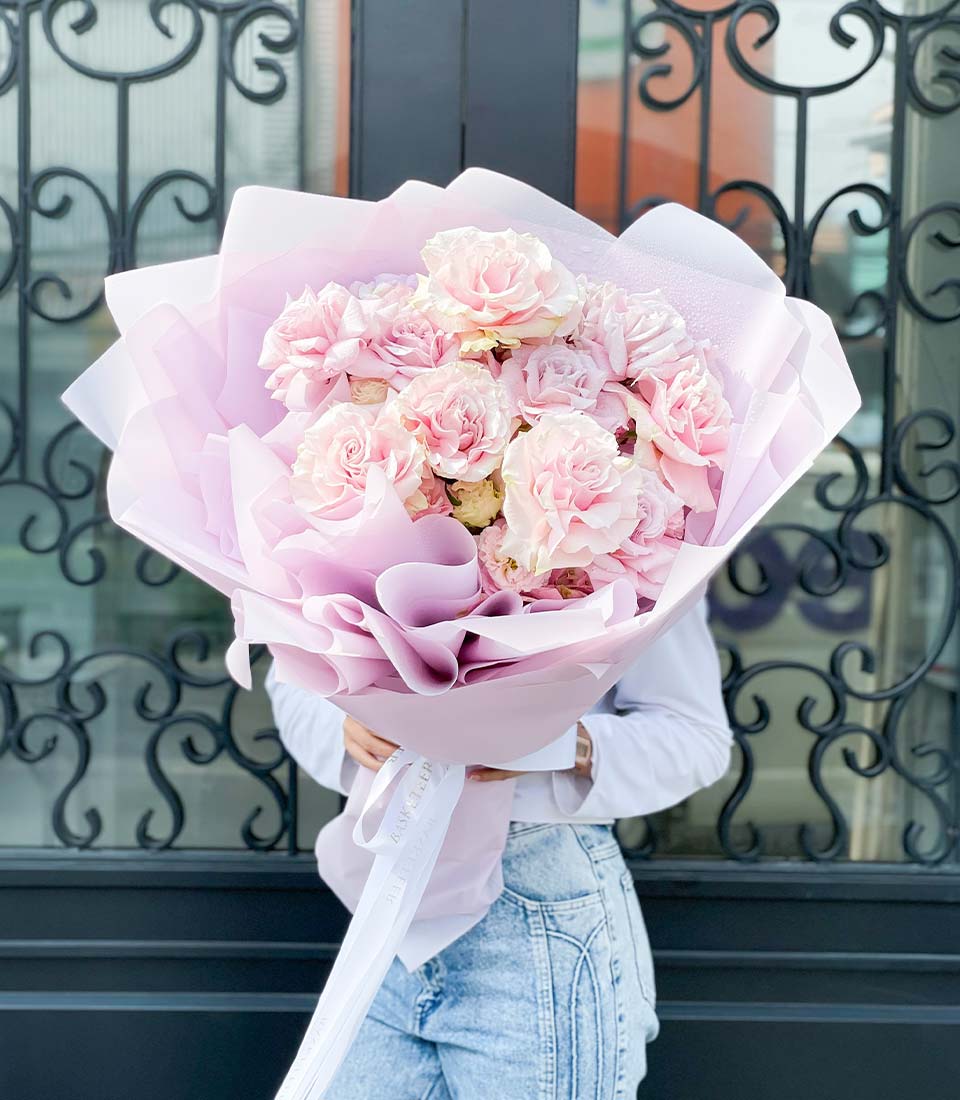 Large light pink rose bouquet wrapped in lavender and white paper with white ribbon, birthday flower gift