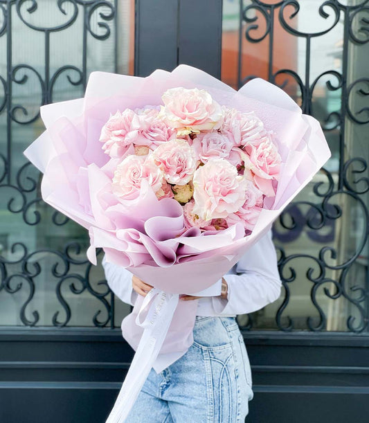 Large light pink rose bouquet wrapped in lavender and white paper with white ribbon, birthday flower gift