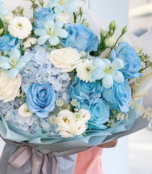 Serene blue and white fresh flower bouquet with roses, hydrangeas, and daisies in premium wrapping